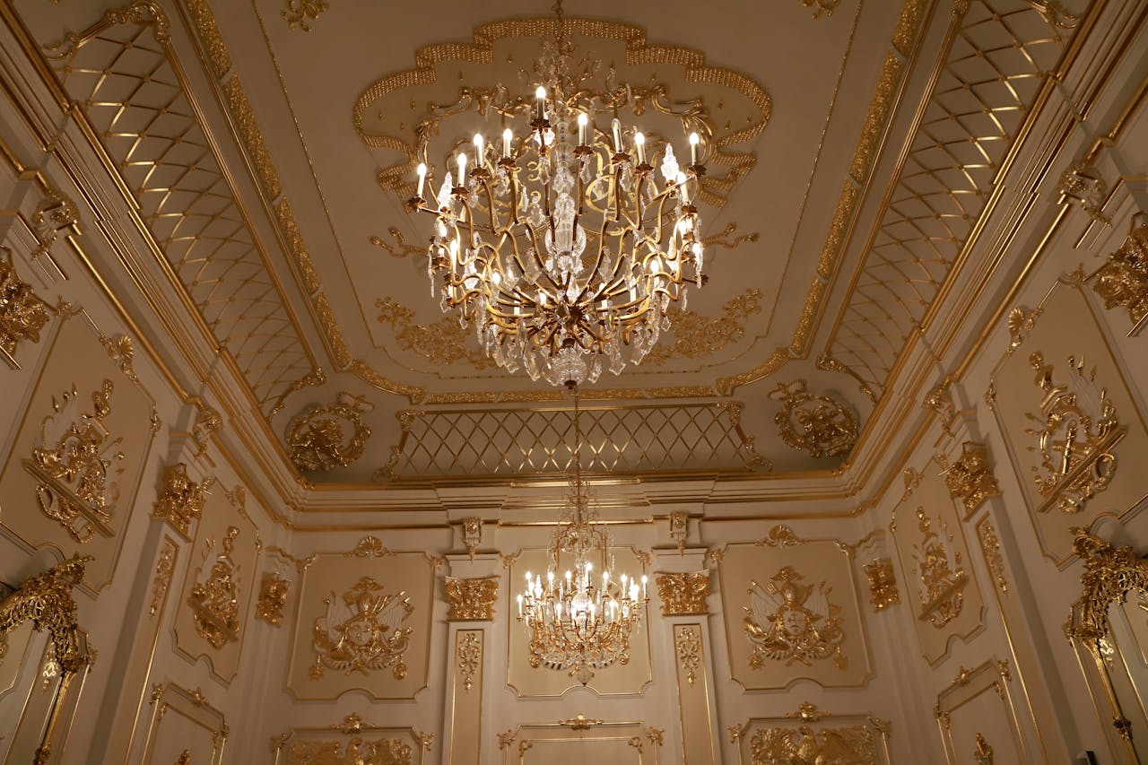 Majestic view of a golden chandelier in an ornate, vintage palace room with intricate detailing.